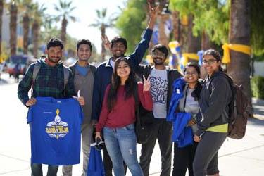 A group of international students stands outside on the campus of 菠菜网lol正规平台 holding Spartan gear.